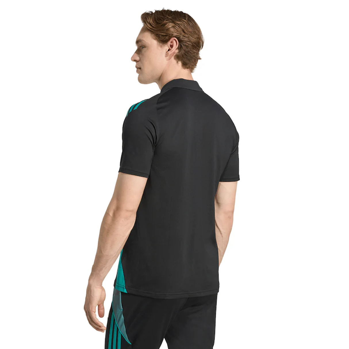 A man stands facing away, wearing the adidas All Blacks 25/26 Training Polo—with blue-green side stripes—and matching black pants.