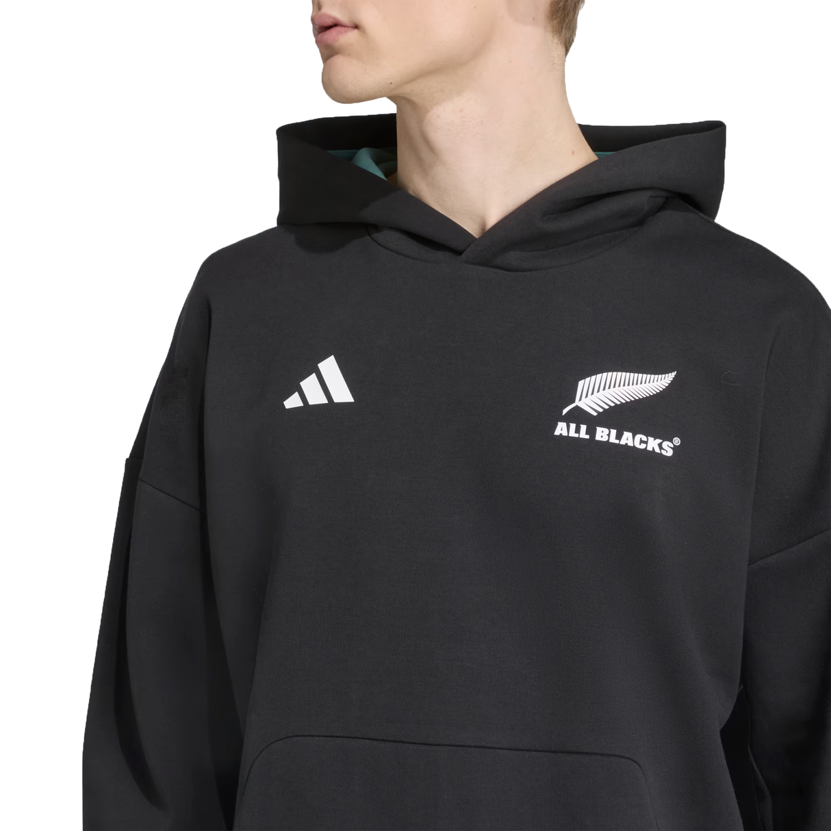 A person wears the All Blacks 25/26 Presentation Jacket by adidas, showcasing the adidas logo on the chest while looking to the side.
