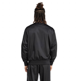 A person with dreadlocks is seen from behind on a white background, wearing the sleek black Originals Limited Edition All Blacks Firebird Track Top made of recycled polyester by adidas, featuring the iconic logo.