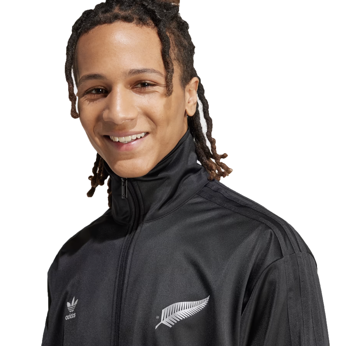 The person is smiling against a white background, wearing the Originals Limited Edition All Blacks Firebird Track Top by adidas, featuring the iconic adidas logo.