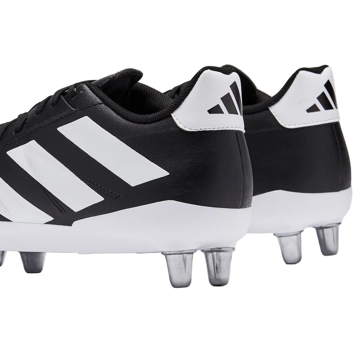 A close-up of two adidas Kakari Elite SG boots in Core Black/White/Core Black, featuring metal studs and detailed views of the side and heel.