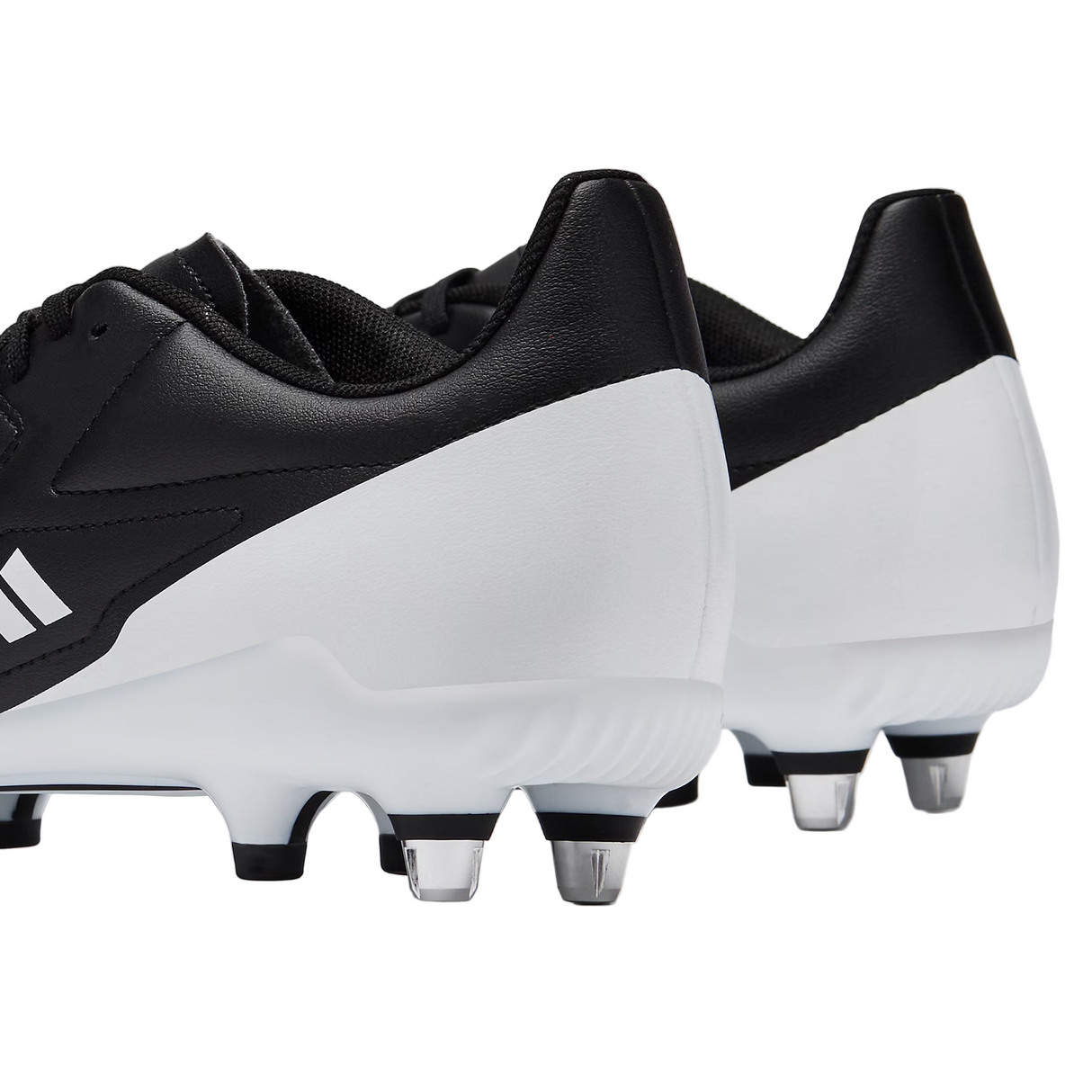 A close-up of the heels and metal studs on the adidas RS15 SG rugby boots in Black/White/Silver, viewed from the back right side.