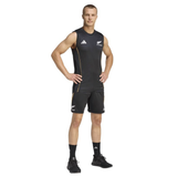 A man stands facing forward with hands on hips, wearing the adidas All Blacks 26/27 Marvel Performance Training Singlet, matching shorts, black socks, and black athletic shoes.