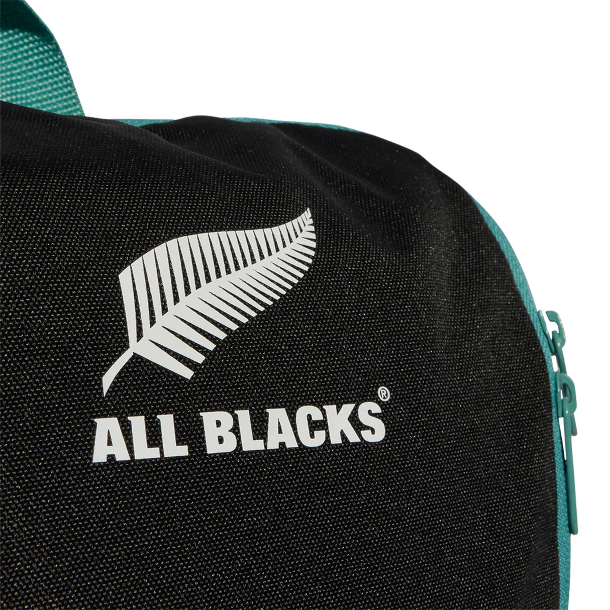 Close-up of the All Blacks 25/26 Backpack by adidas, showing the white fern logo, "ALL BLACKS®" text, and a teal zipper on the right side.