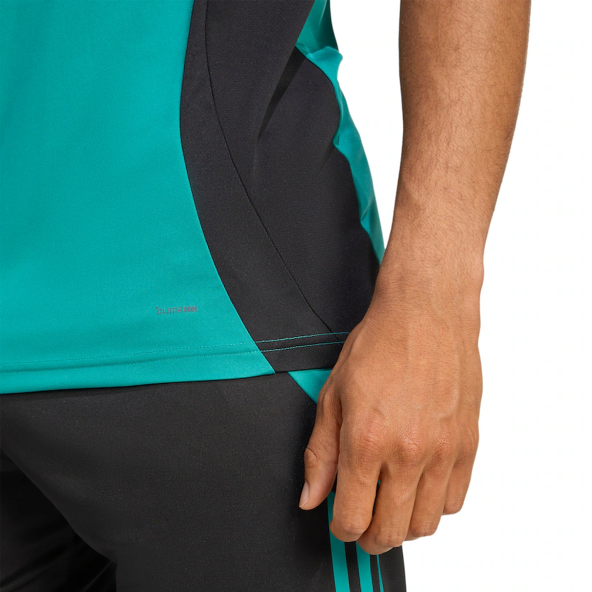 A person wearing the adidas All Blacks 25/26 Training Singlet and black shorts with teal stripes, shown from chest to thigh with one hand relaxed at their side—ideal for rugby training.
