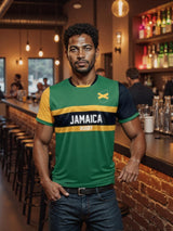 A man in an Admiral "Nations of Rugby Jamaica Supporters Jersey" leans against the dimly lit bar counter with exposed brick walls, surrounded by bar stools and softly glowing lights, proudly wearing his Nations of Rugby spirit.