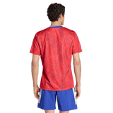 A man faces away from the camera, wearing an adidas France Rugby Prematch Jersey with Climacool technology and blue athletic shorts with white accents.