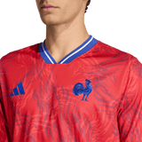 A person wearing the France Rugby Prematch Jersey by adidas, featuring blue accents, a blue rooster emblem, the adidas logo on the chest, and Climacool technology for enhanced comfort.