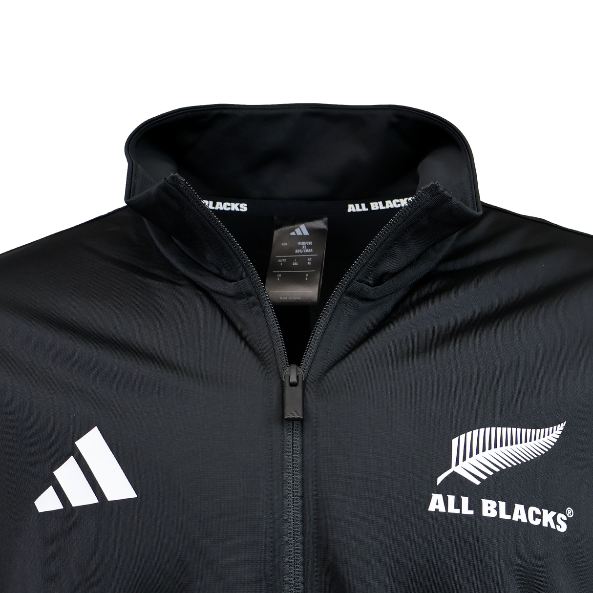 Close-up of a black adidas All Blacks 26/27 Marvel Track Top, featuring the adidas logo and All Blacks silver fern emblem on the chest, with a tag inside the collar—part of the exclusive Marvel Track Top collection.