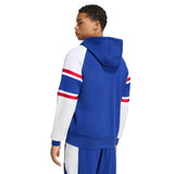 A man seen from the back is wearing the France FFR 26/27 Travel Full Zip Hoodie by adidas in blue with white sleeves and red stripes, paired with matching blue and white pants.