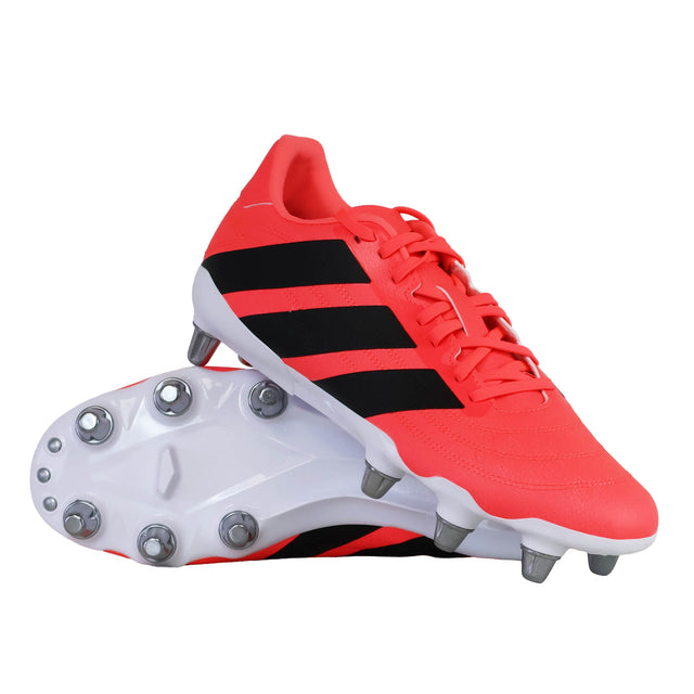 A pair of vibrant pink adidas-Kakari SG Rugby Boots, featuring black stripes and white accents, one positioned upright while the other lies on its side to display the sole—these boots are crafted by adidas for exceptional traction on soft ground.