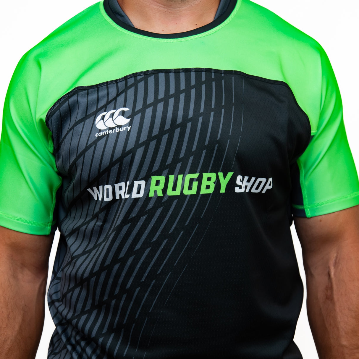 A person wearing the Teamatical Canterbury Elite Full Custom Sublimated Jersey for men, featuring black and green colors with "WORLD RUGBY SHOP" and the Canterbury logo on the front.