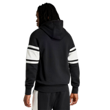 A person is seen from the back against a plain background, wearing the adidas All Blacks 26/27 Travel Full Zip Hoodie with white and black striped sleeves and black pants with a white stripe.