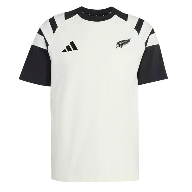 The All Blacks 26/27 Travel T-Shirt by adidas is a white and black short-sleeve shirt featuring a striking black fern and the adidas logo on the chest, along with bold black angled stripes on the shoulders—a classic look inspired by the iconic New Zealand rugby shirt.