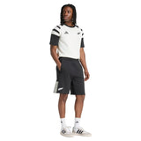 A person wearing the adidas All Blacks 26/27 Travel T-Shirt, paired with black and white adidas shorts, socks, and sneakers, stands against a white background.