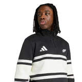 Wearing the All Blacks 26/27 Leisurewear 1/4 Zip Sweatshirt by adidas, a person gazes to the side against a plain background. The black and white sweatshirt features adidas logos and signature white stripes.