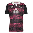 Introducing the All Blacks 26/27 Training Jersey - South Africa Tour by adidas: a short-sleeve rugby jersey featuring a crisp white collar, bold black sleeves, and an eye-catching pink and purple leaf pattern. This adidas design displays the All Blacks, adidas, and Toyota logos on the front and is crafted as an official training jersey inspired by the All Blacks’ tour of South Africa.