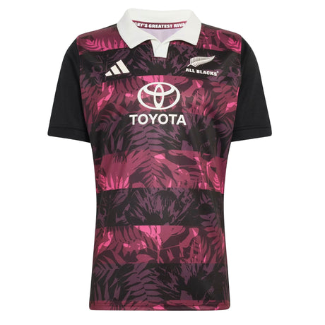 Introducing the All Blacks 26/27 Training Jersey - South Africa Tour by adidas: a short-sleeve rugby jersey featuring a crisp white collar, bold black sleeves, and an eye-catching pink and purple leaf pattern. This adidas design displays the All Blacks, adidas, and Toyota logos on the front and is crafted as an official training jersey inspired by the All Blacks’ tour of South Africa.