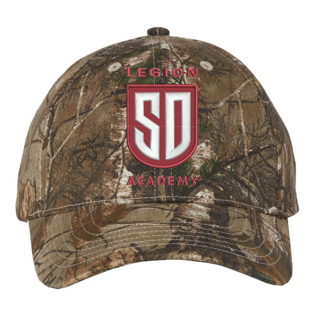 Legion Academy Realtree Camo Cap in a brown and green camouflage pattern, featuring a shield-shaped logo that reads “LEGION” and “ACADEMY” with the letters “SD” in the center.