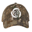 The Missoula All-Maggots Realtree Camo Cap by EMB S&S Activewear features a distinctive white spiral pattern on the front that resembles teeth or a fossil. This adjustable cap blends unique design with classic outdoor style.