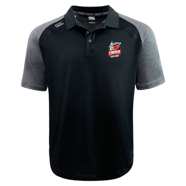 The Lincoln City Youth Rugby Elite Polo by EMB Canterbury features black and gray short sleeves, the Lincoln Fire & Rescue logo on the left chest, Canterbury logo on the right shoulder, and moisture-wicking Vapodri fabric.
