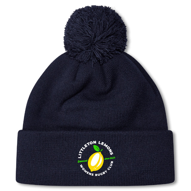 The Littleton Women Rugby Club Pom Pom Beanie by Canterbury features navy blue fleece lining, a pom-pom, and the club's yellow lemon logo on the front cuff. Brand: EMB Canterbury.
