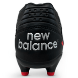 Back side of black rugby boot with silver new balance on the back and red studs.