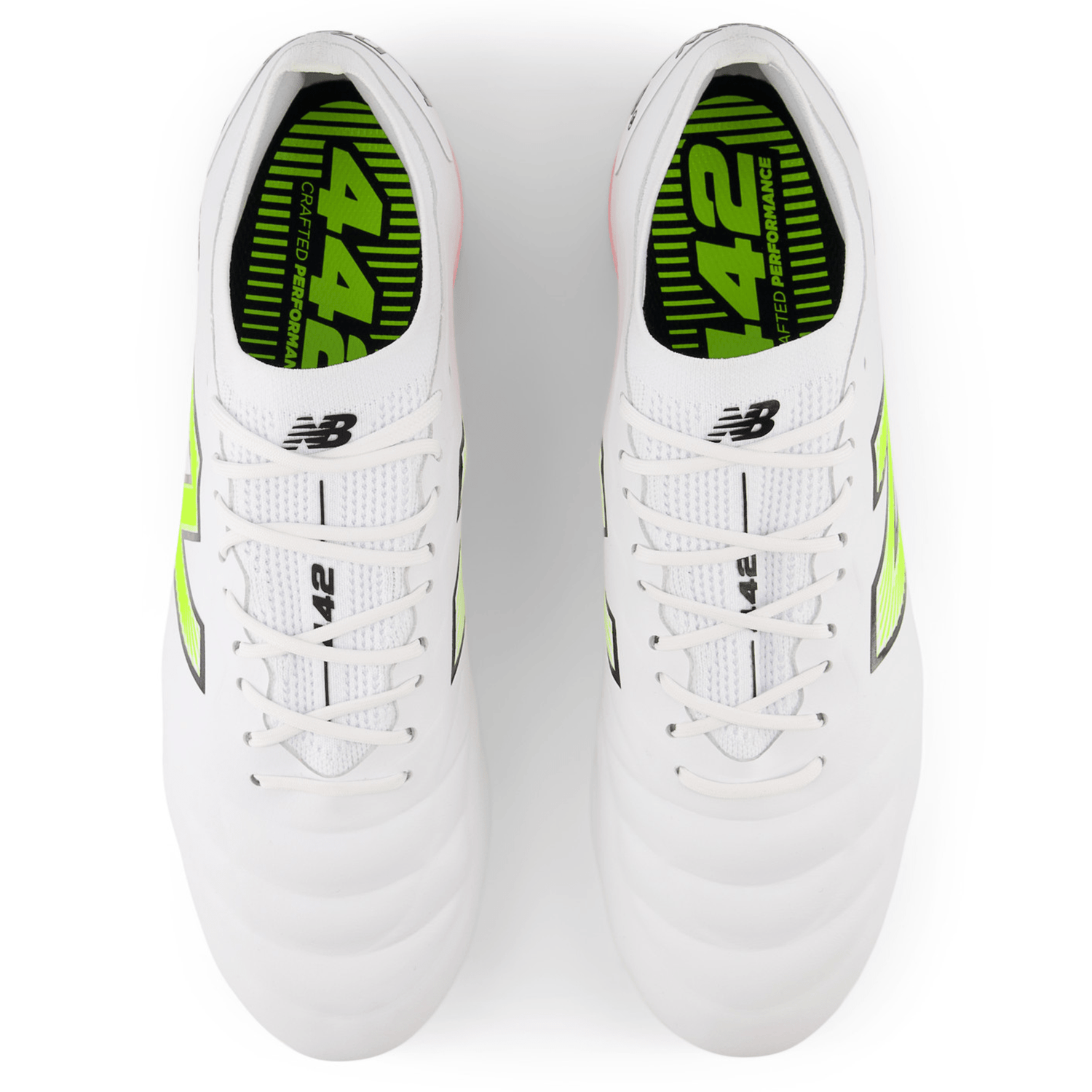 Aerial view of the New Balance 442 v2 Elite FG sports shoes, showcasing white microfiber with Energy Red and Hi-Lite accents resembling a rugby cleat, and the "442" text on the insoles.