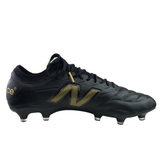 New Balance 442 v2 Elite FG Wide Boots in black with metallic gold accents feature a prominent side logo and metal studs for firm ground grip.