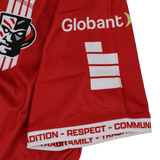 Close-up of a Utah Warriors MLR 25/26 Replica Away Jersey sleeve by Macron, showing the logo, "Globant," white stripes, and "TRADITION - RESPECT - COMMUNITY - FAMILY" printed along the cuff.