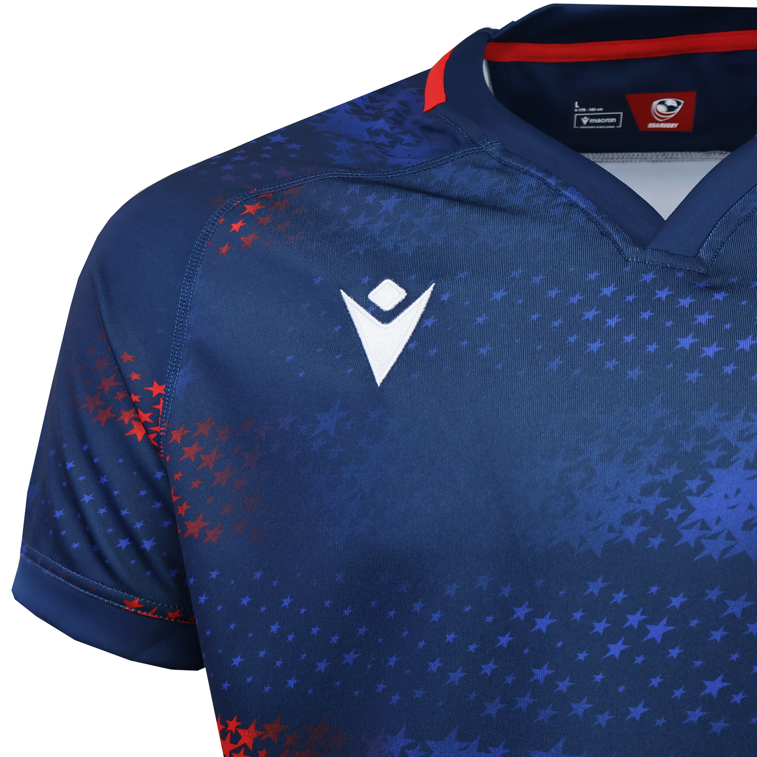 The USA Rugby 25/26 Away Replica Jersey by Macron features a navy blue base with red and blue star patterns, a white Macron logo on the chest, and a bold red collar accent.
