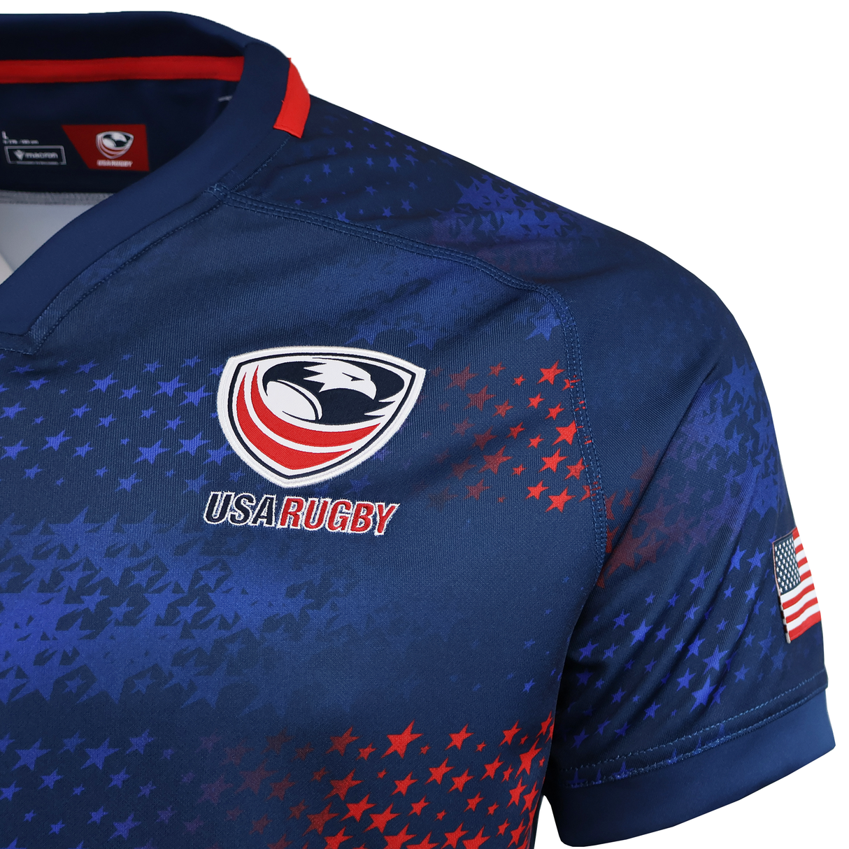 A close-up of the USA Rugby 25/26 Away Replica Jersey by Macron, a blue patriotic rugby jersey with the USA Rugby logo, red and blue star patterns, and an American flag patch on the sleeve.