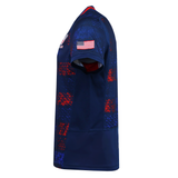 The USA Rugby 25/26 Away Replica Jersey by Macron features red and blue checkered patterns, a USA flag patch on the sleeve, and is shown from a side view. This patriotic Macron jersey is perfect for showing your team spirit.