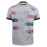 The USA Rugby 25/26 Home Replica Jersey by Macron features white short sleeves, bold red and blue star patterns, and "USA" embossed on the lower back—a must-have for fans wanting an authentic Macron USA Rugby look.
