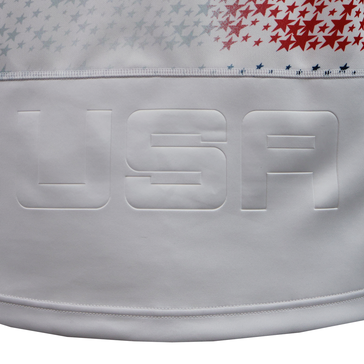 Close-up of the USA Rugby 25/26 Home Replica Jersey by Macron, featuring "USA" embossed and a pattern of small red, blue, and gray stars above it—a classic look from Macron's home jersey.