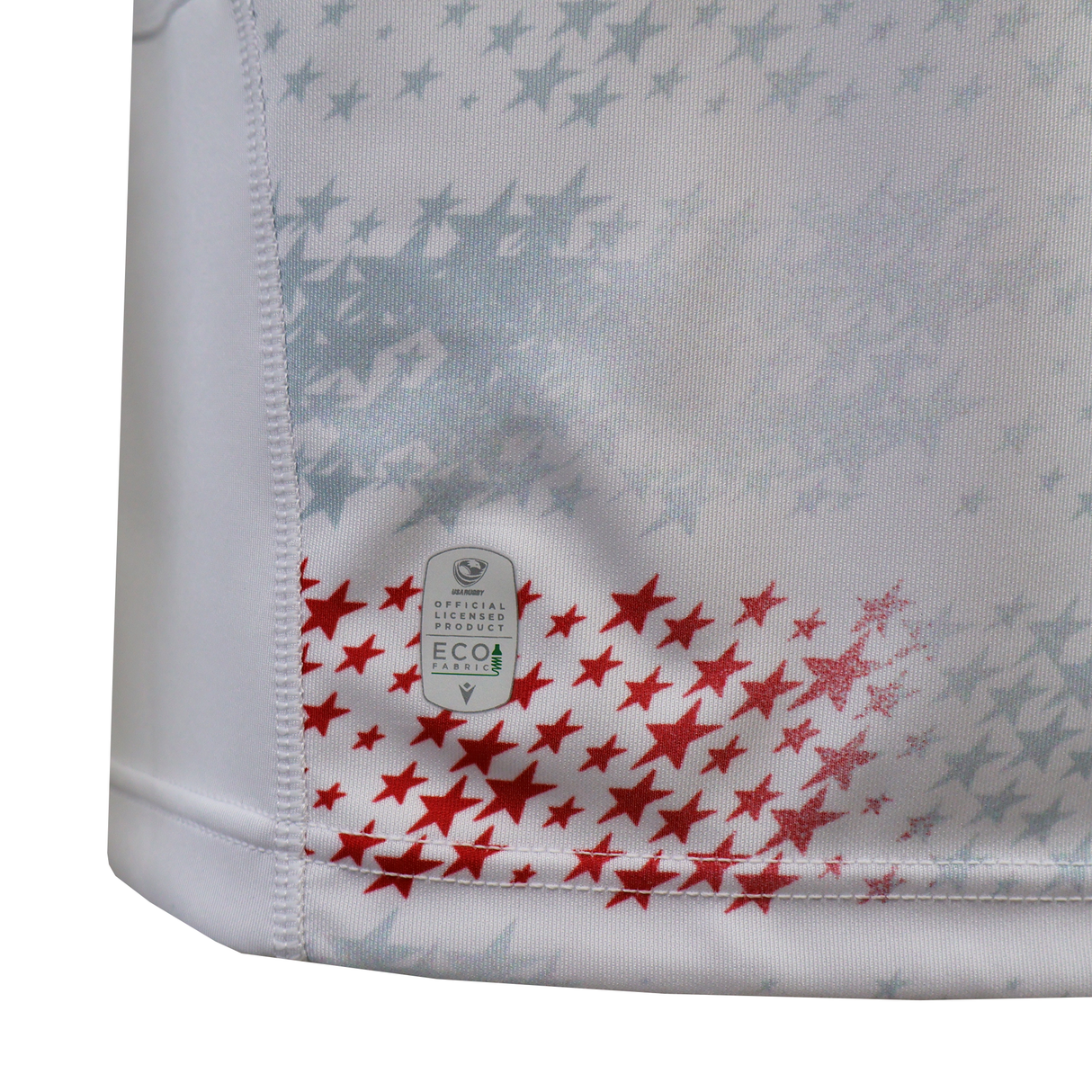Close-up of white fabric with red and gray stars and an "Eco" tag near the hem, from the USA Rugby 25/26 Home Replica Jersey by Macron.