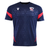 The USA Rugby 25/26 Training Poly Shirt by Macron features navy blue with diamond patterns, red sleeve and side accents, breathable Poly Dry fabric, and displays a bird logo plus "USA Rugby" text on the chest.