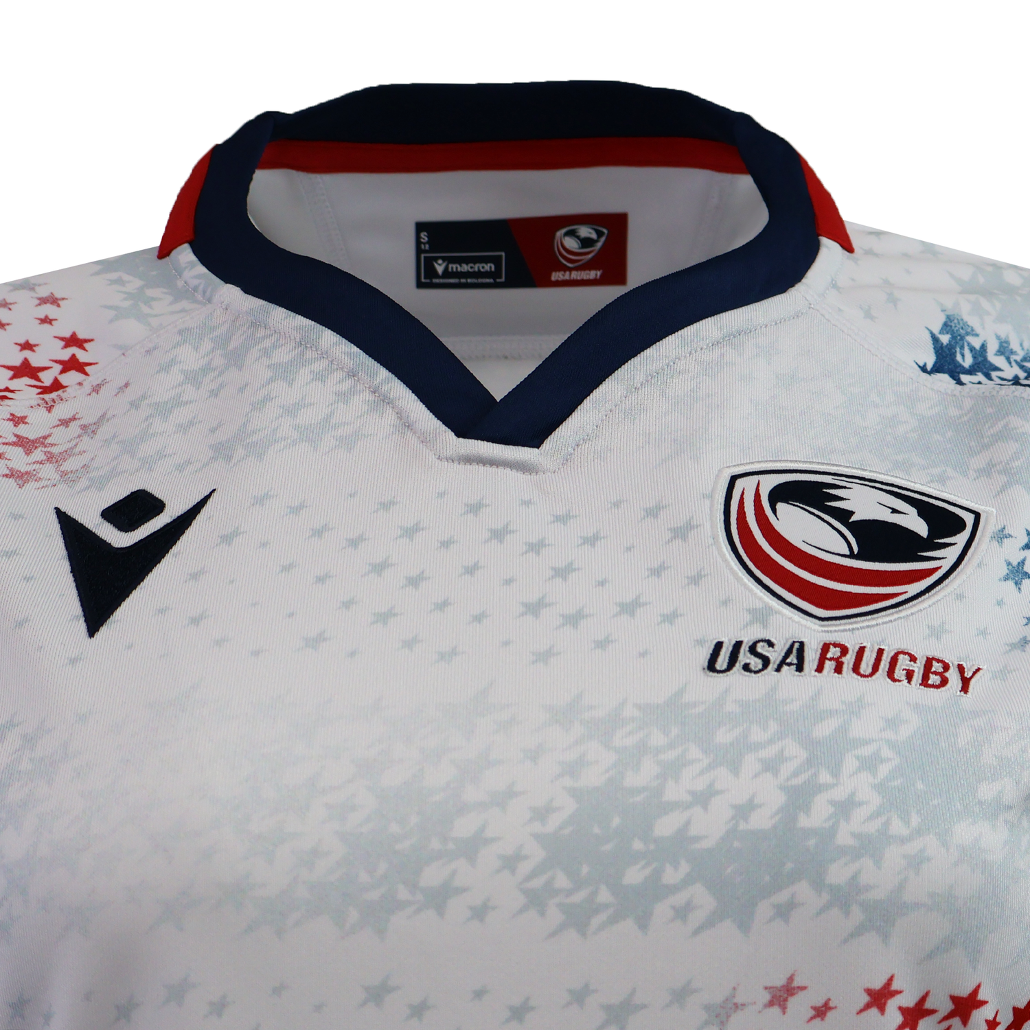 Close-up of the Women's USA Rugby 25/26 Home Replica Jersey by Macron, featuring a white design with the eagle logo, red and blue trim, star patterns, and official Macron branding on the chest.