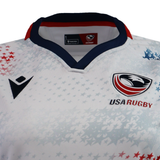 Close-up of the Women's USA Rugby 25/26 Home Replica Jersey by Macron, featuring a white design with the eagle logo, red and blue trim, star patterns, and official Macron branding on the chest.