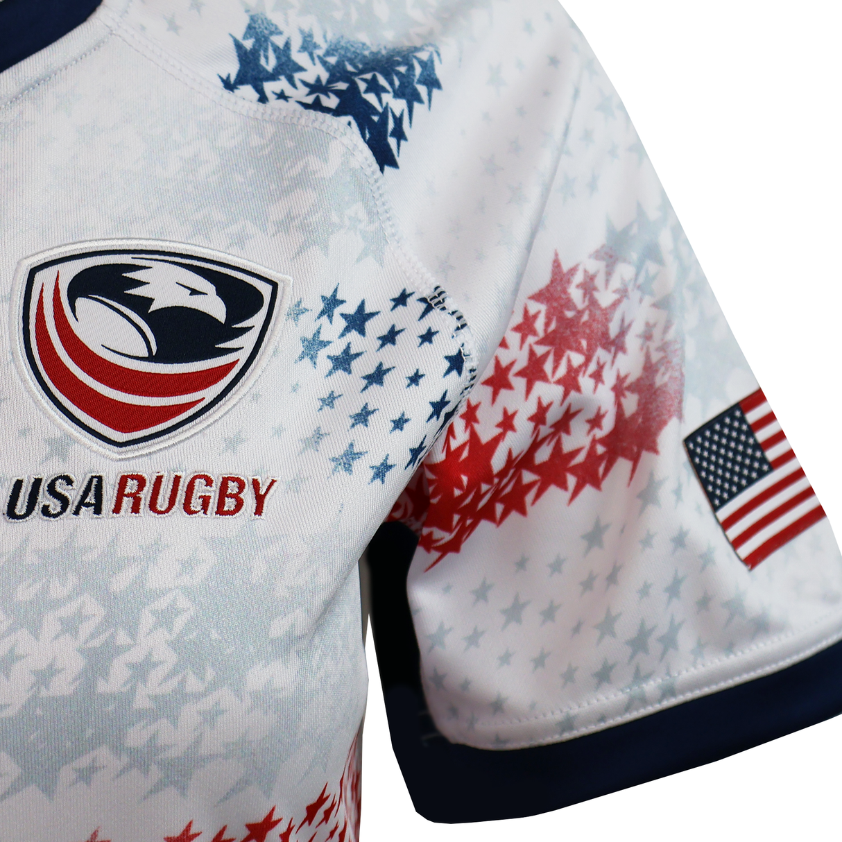 Close-up of the Women's USA Rugby M25/26 Home Replica Jersey by Macron, featuring a stylized eagle logo, red and blue star patterns, and an American flag patch on the sleeve—ideal for fans wanting an authentic Macron jersey.