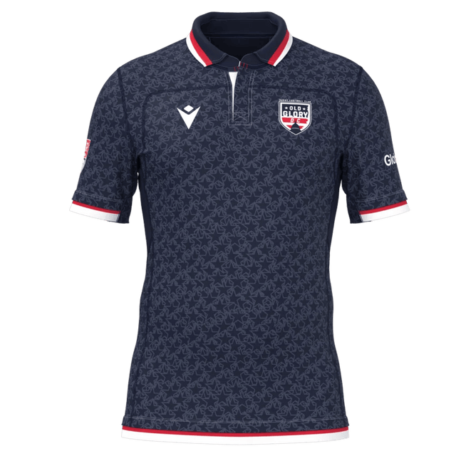 The Old Glory DC MLR 25/26 Replica Home Jersey by Macron features a navy blue design with a subtle pattern, red and white collar and cuffs, and the "Glory" team logo on the left chest.