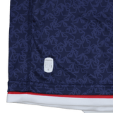 Close-up of the Old Glory DC MLR 25/26 Replica Home Jersey by Macron—navy blue with geometric patterns, red and white trim, and an Eco logo patch—an authentic fan replica from Macron.
