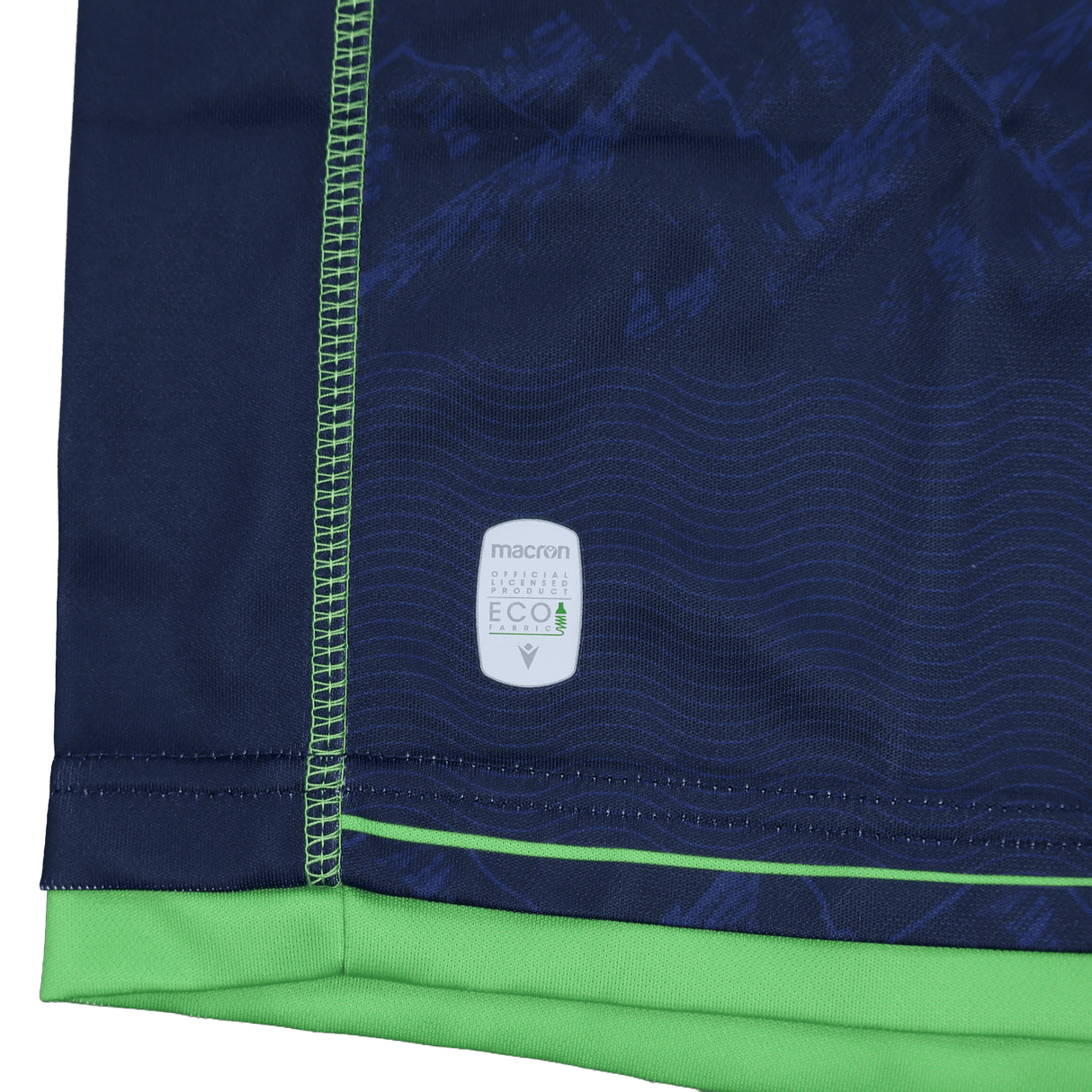Close-up of the Seattle Seawolves MLR 25/26 Replica Home Jersey by Macron, featuring navy blue and green fabric, visible stitching, and a white "Macron Eco" label near the hem.