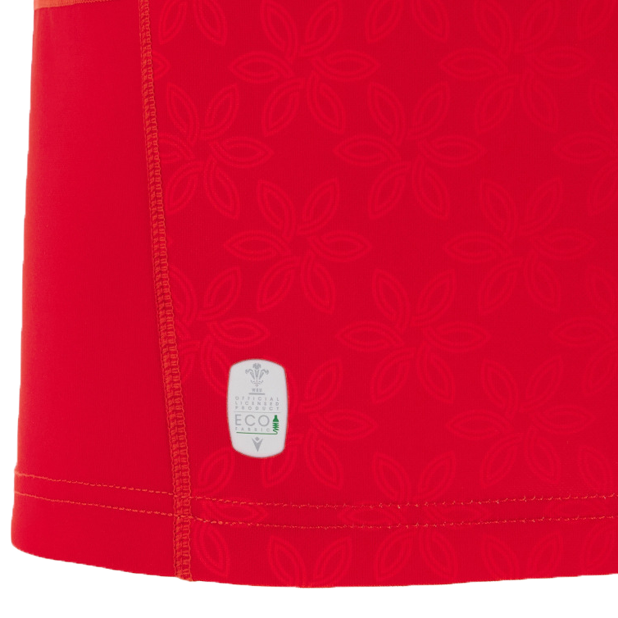 Close-up of the Wales WRWC25 Replica Home Jersey by Macron shows its red fabric with a subtle floral geometric pattern, visible stitching, and an "ECO" label—ideal for Welsh rugby fans and the Women’s Rugby World Cup 2025.