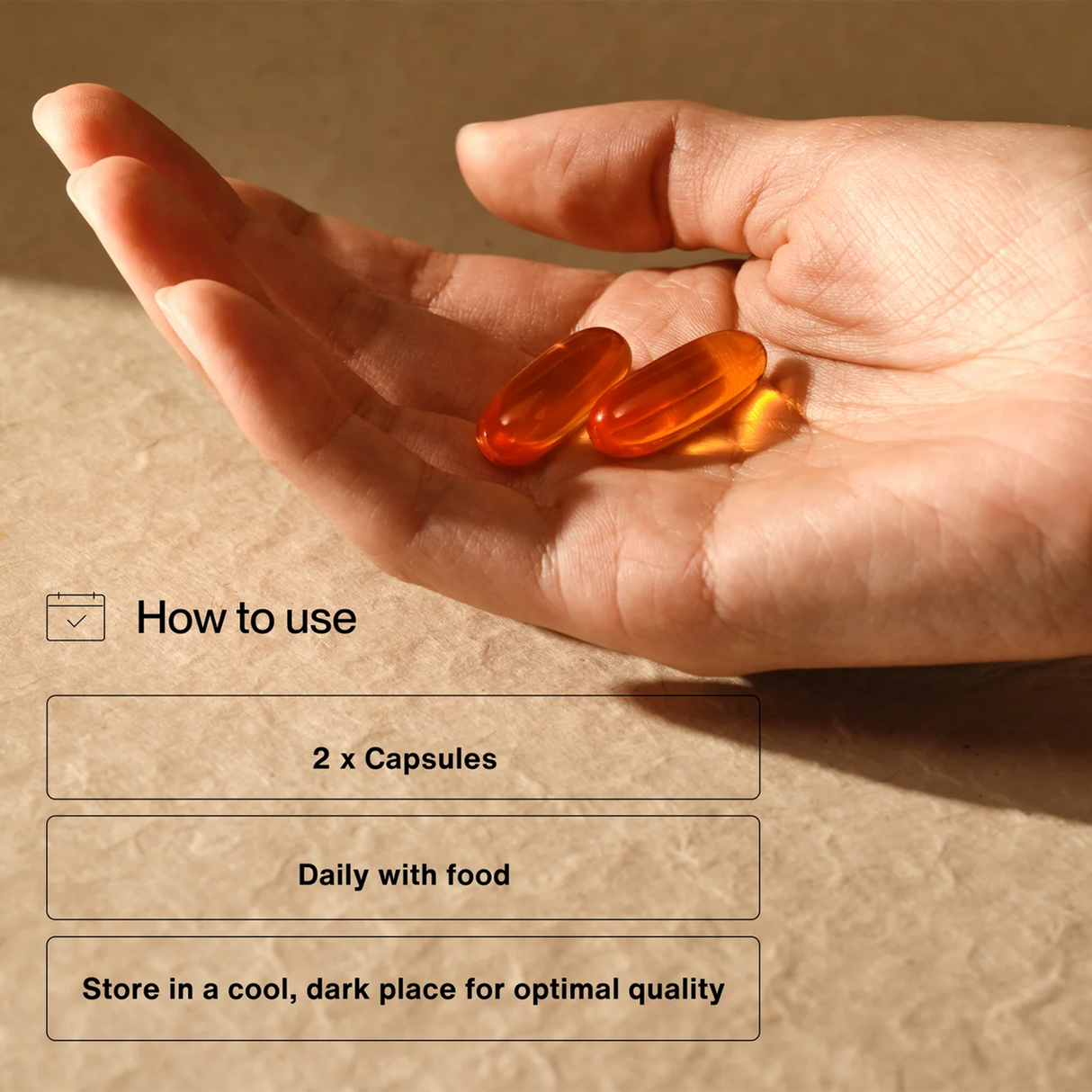 A hand holds two orange Momentous OMEGA-3 capsules above usage instructions: take 2 capsules daily with food to support joint health and recovery; store in a cool, dark place. Contains 30 servings per container.