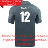 The back of a grey Springboks 26/27 Greatest Rivalry T-Shirt by Nike displays the white text “NAME” and the number “12,” demonstrating personalization placement in a classic style. Text overlay indicates that the actual Nike product may vary.