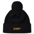 The Norwich University Women's Rugby Pom Pom Beanie by EMB Canterbury is a black knit hat with a pom-pom and "N Women's Rugby" embroidered in yellow and red, perfect for showing team spirit.