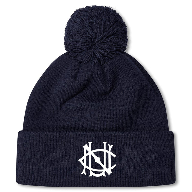 The UNC Rugby Pom Pom Beanie by EMB Canterbury is a navy fleece-lined beanie with a pom-pom and white interlocking letter logo on the folded brim.