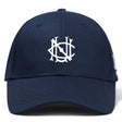 The UNC Rugby Flexfit Drill Cap by EMB Canterbury is a navy blue curved brim cap with a white embroidered stylized overlapping NS logo on the front panel.