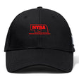 The Nebraska Youth Rugby Association Flexfit Drill Cap by EMB Canterbury is a black cap with a curved brim, featuring an embroidered red Nebraska outline, "NYRA" text, and a rugby ball logo on the front.